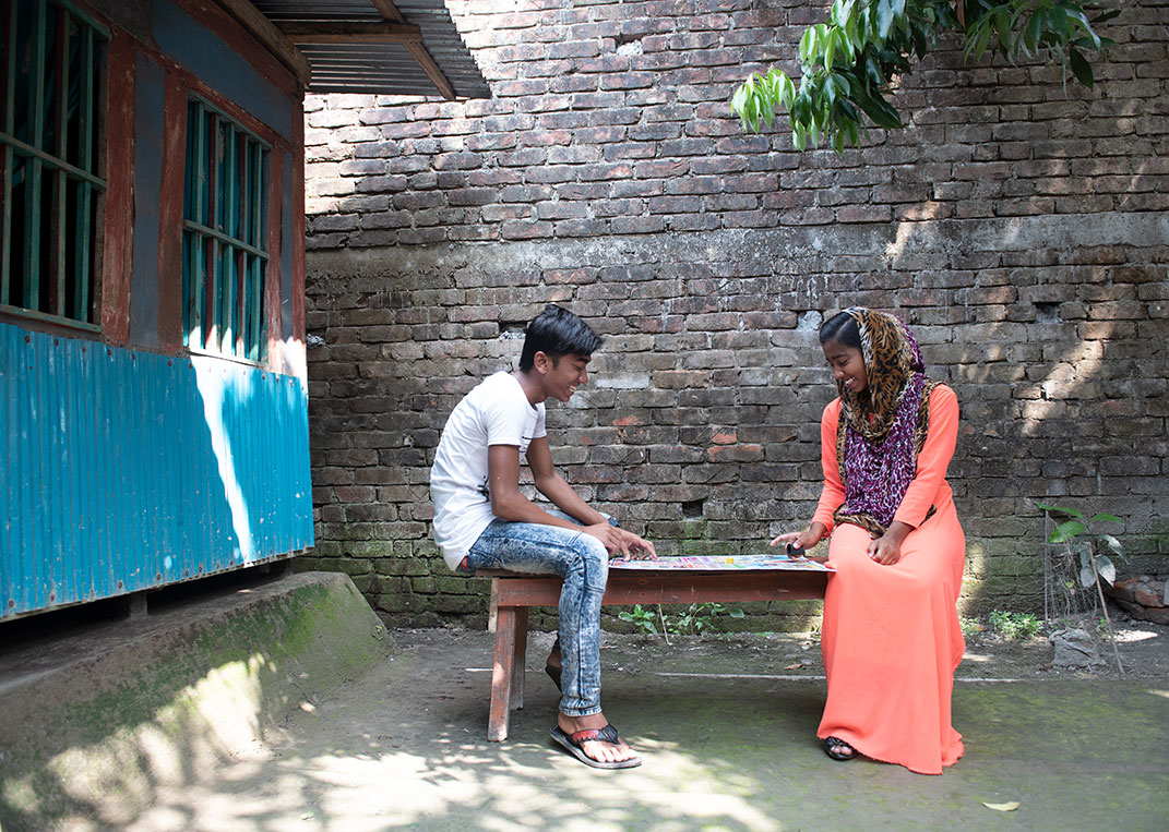 3 girls sit in the waiting room of a Plan International-supported clinic