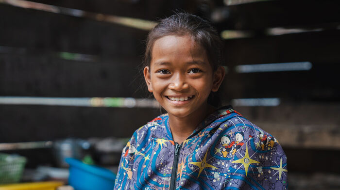 An 11-year-old girl sits in her home in Cambodia.