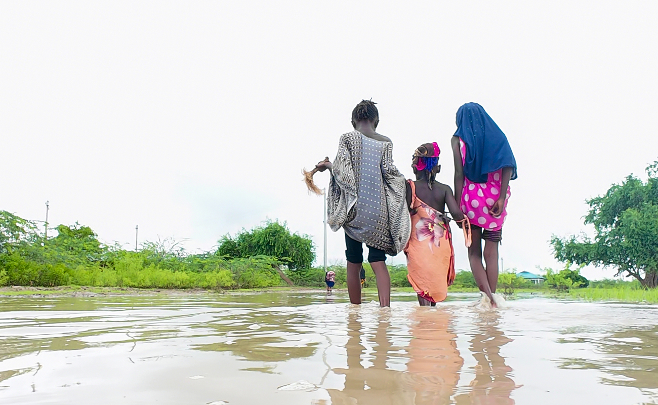 A photo of three children walking through muddy water after floods in Tana River County in Kenya.