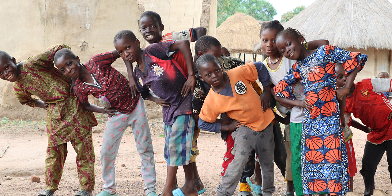 group of young black children standing in a row and stretching to the left while smiling