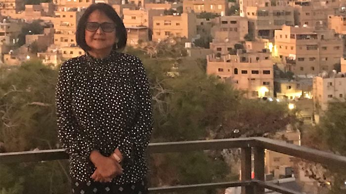 woman standing on a balcony over looking over a city