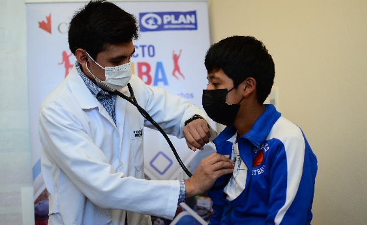 A health care worker listens to a boy’s heart and lungs in a health facility in Bolivia.