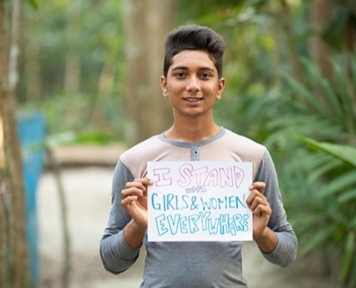 Boy holding sign saying I stand for Girls and Women everywhere