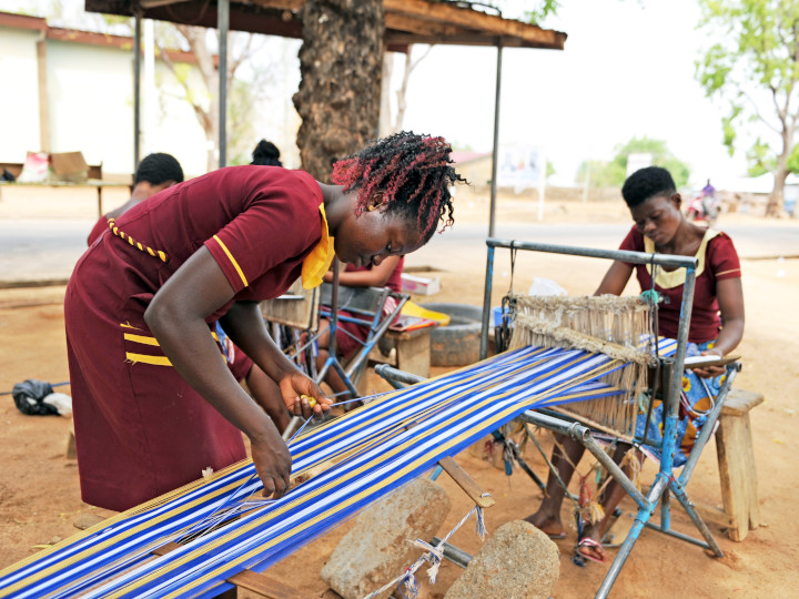 Girls weave cloth together which they sell at the local market  