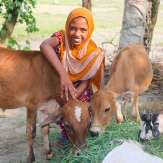 Smiling woman feeding goats outdoors