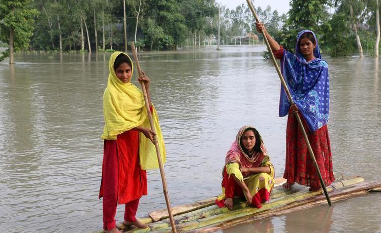 Girls paddle a homemade raft in their flooded community in Bangladesh which is affected by climate change.