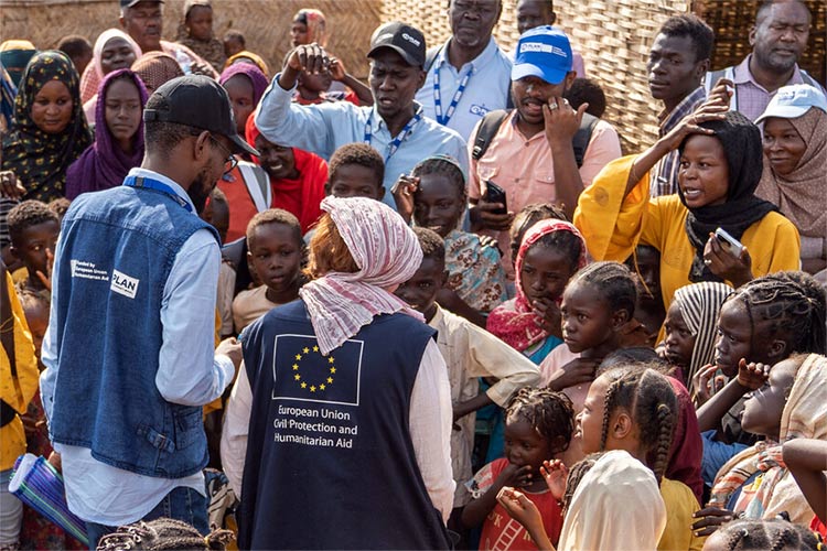 Children and families walk through a crowded area carrying their belongings.  Campaign to raise donations for GAZA EMERGENCY APPEAL.