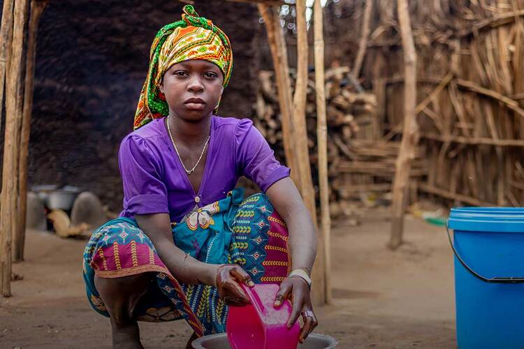 Beti, 15, washes dishes outside the family's shelter