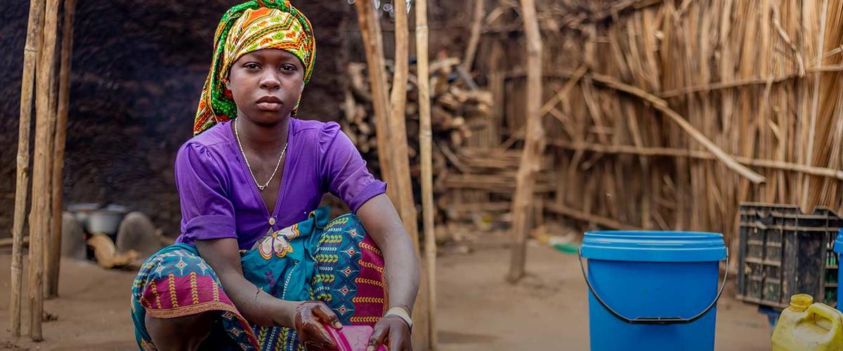 Beti, 15, washes dishes outside the family's shelter