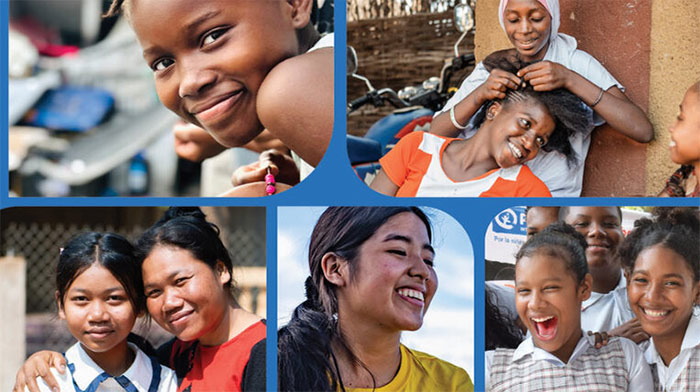 A girl in a white shirt holds her first up in the air against a background of the sky