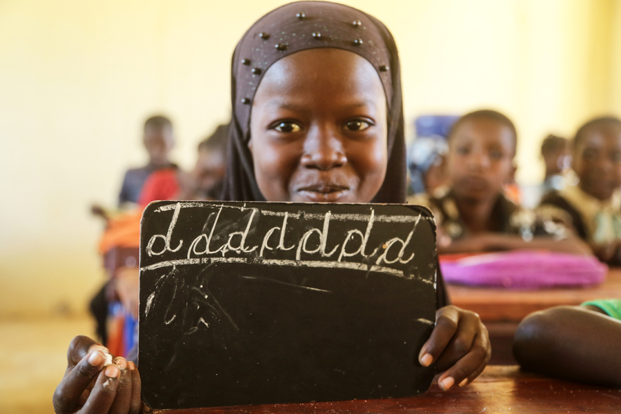 Girl writes on blackboard in her classroom in Mali.