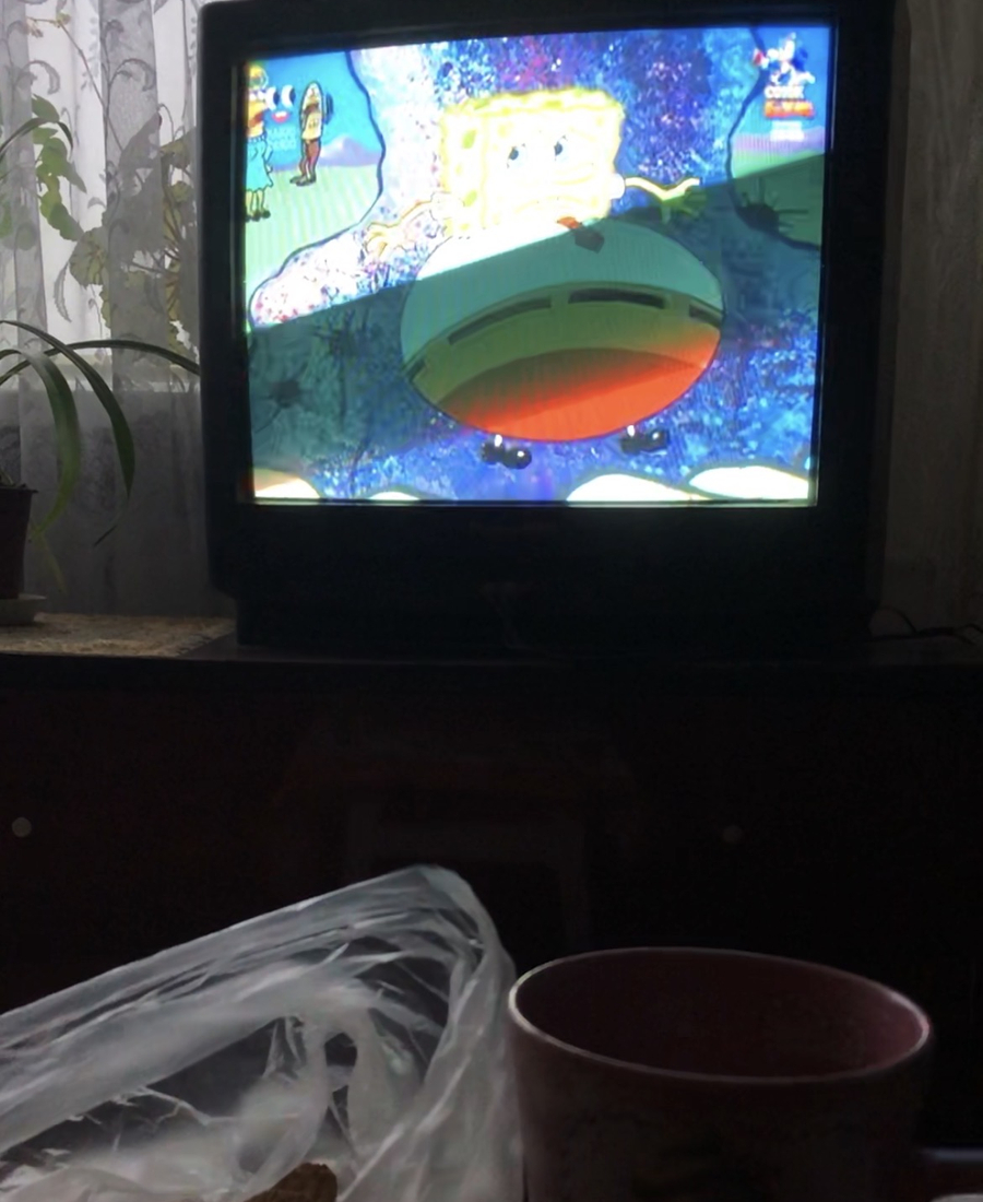 A cup, with a television in the background