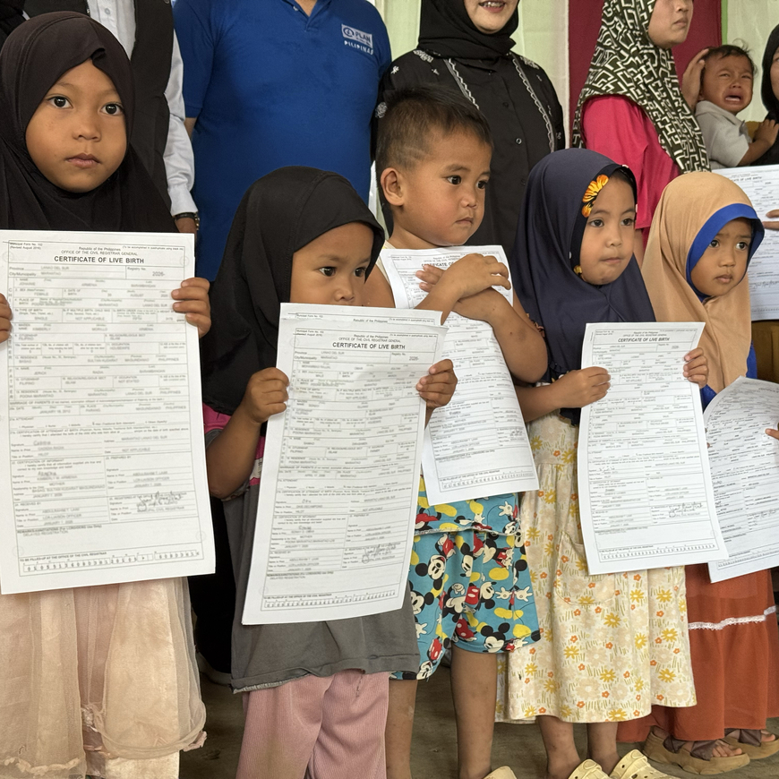 A group of seven children hold newly issued birth certificates during a community birth registration event in Lanao del Sur, Philippines.