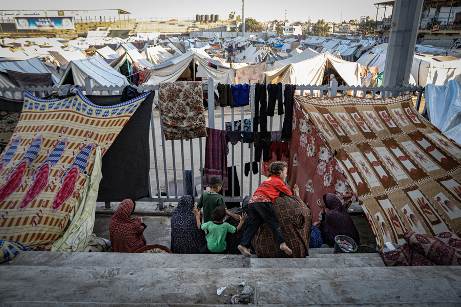 A family sits on the steps of a sports stadium in Gaza, where displacement camps have been set up.