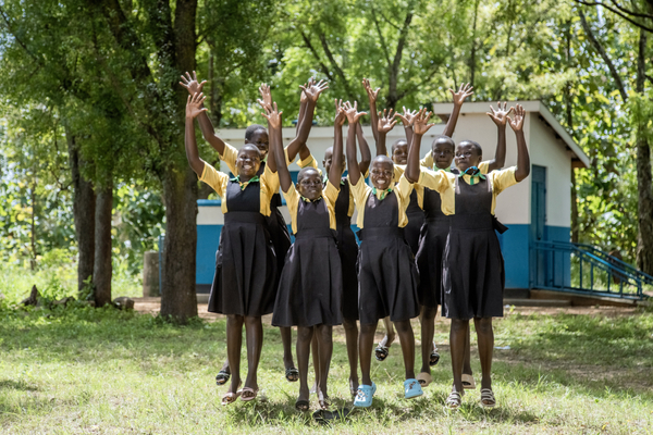 Girls jump for joy in front of their new toilet block