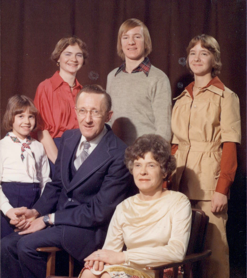A family photo of six people, including three young adults and one child.