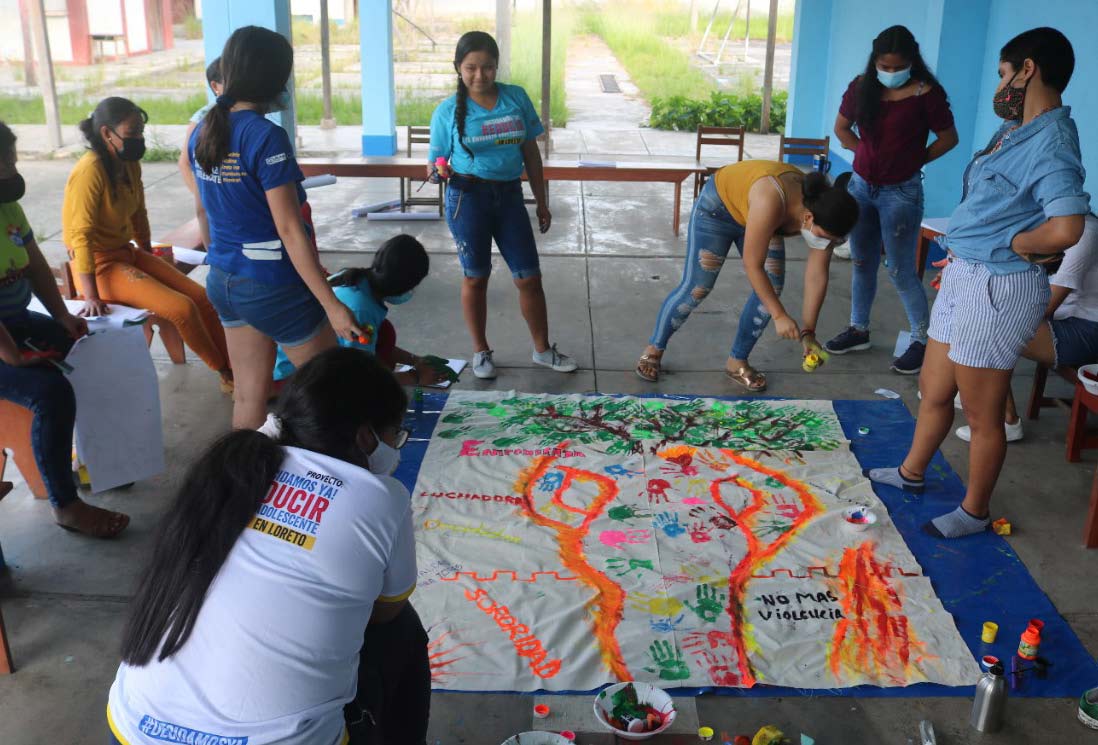 Youths creating a mural to denouncegender-based violence and inequality for the regional government of Loreto.