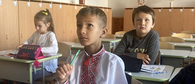 three children sitting in a classroom looking up