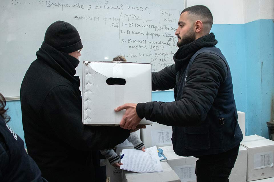 A man hands another man a large box.