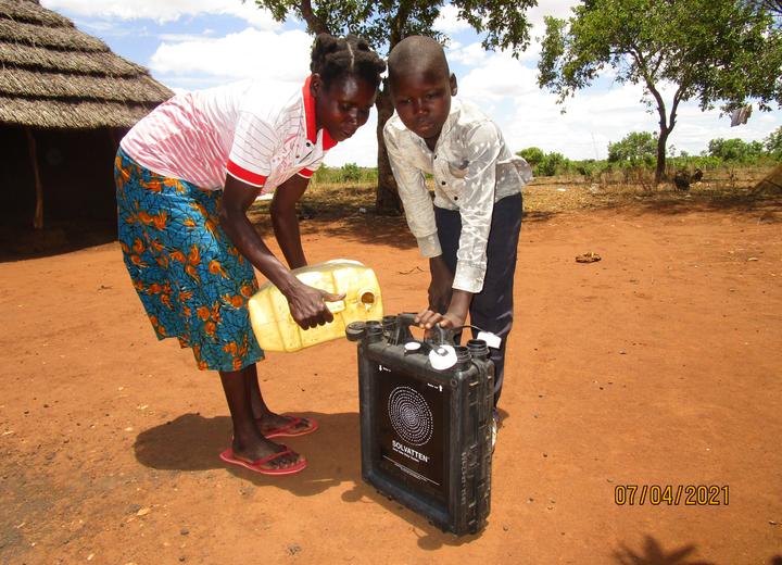 A boy and his mother use a clean water kit in Uganda