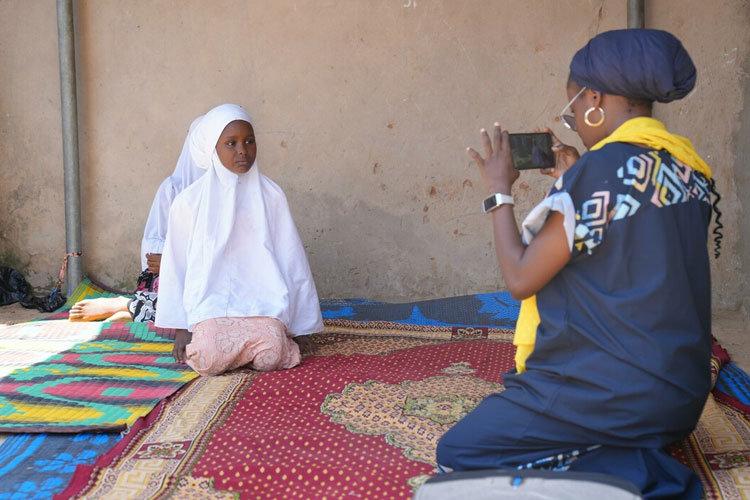 A girl is filmed by a woman using an iPhone.