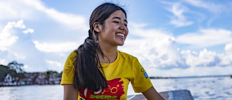 girl with long black ponytail smiling on a boat