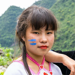 Young girl with blue face paint in a mountainous landscape