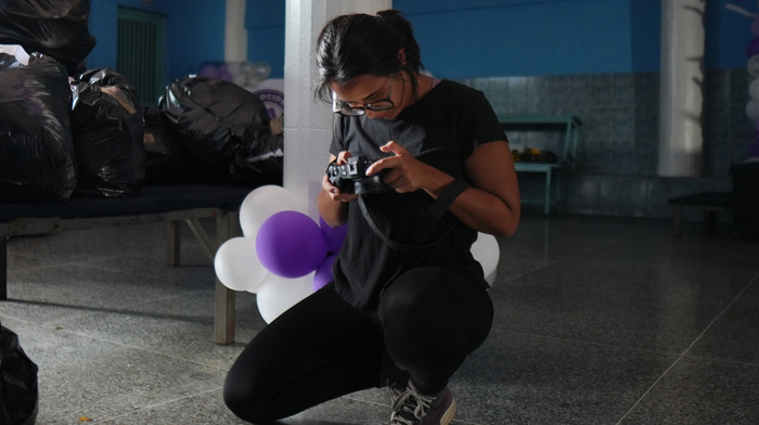 A young woman kneeling down and looking at her camera