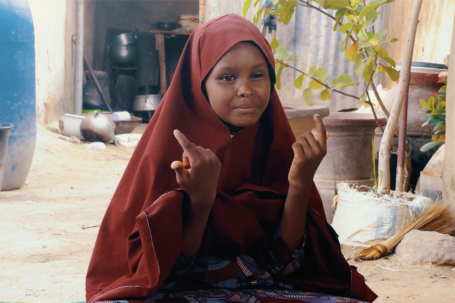 Salma uses the sign language to the camera with a smile on her face. 