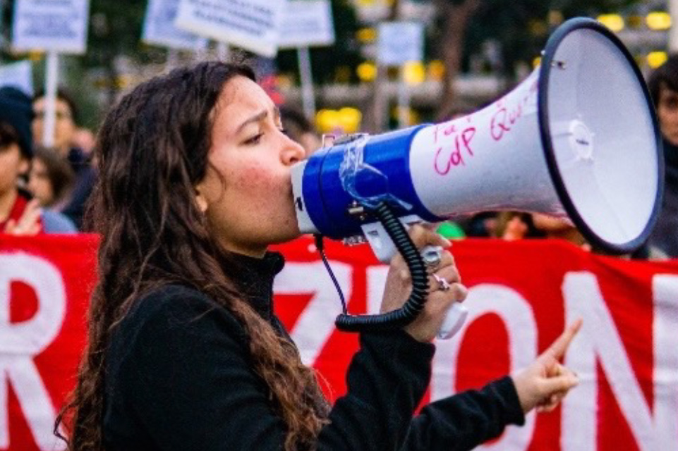 A woman speaking into a megaphone at a protest