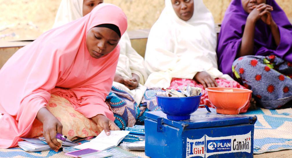 A woman sorts chequebooks and money during a VSLA meeting in Nigeria.