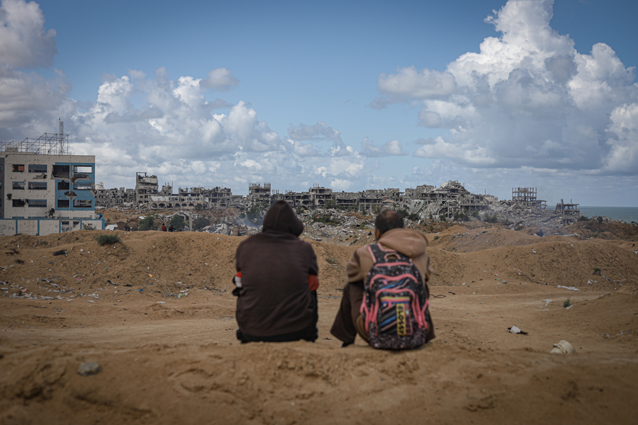 Two men wait for an airplane delivering aid supplies to Gaza.