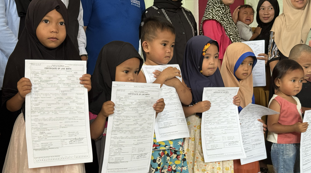 A group of seven children hold newly issued birth certificates during a community birth registration event in Lanao del Sur, Philippines.