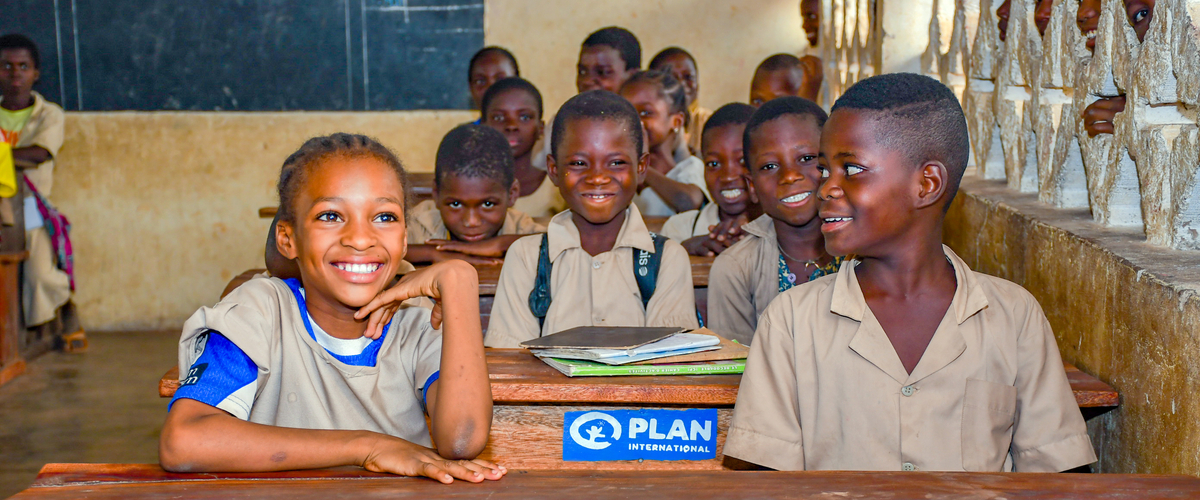 Children learn in class provided with desks and benches by Plan International