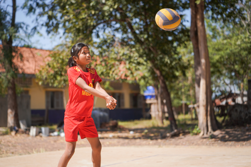 Sreylen, an 11-year-old girl, hits a volleyball during a game outside at her school.