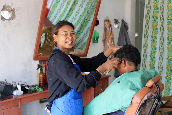 Devi, 24, cuts man's hair at her salon set up with the support of Plan 