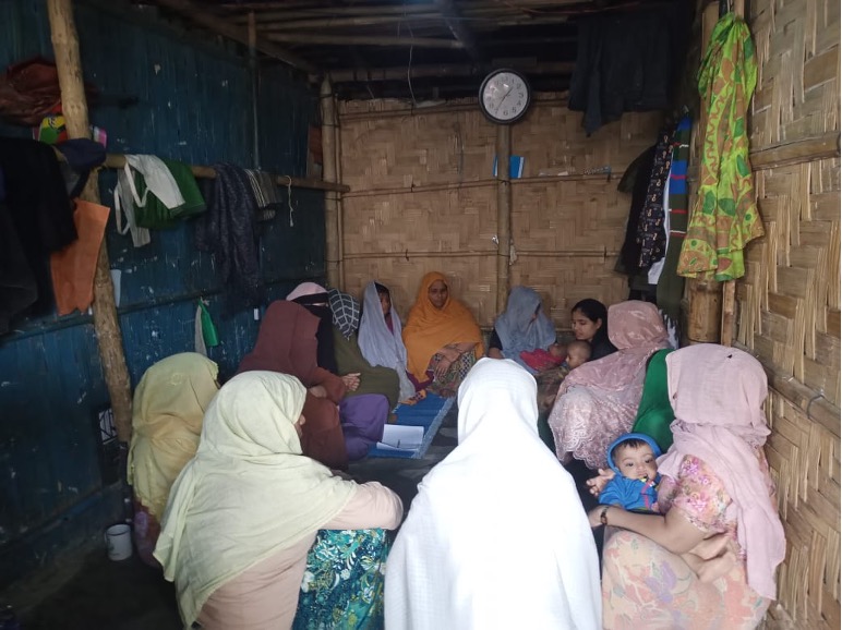 A group of women wearing hijabs and burqas sitting together talking to each other.