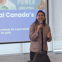 Woman speaking into a microphone at a Plan International Canada event