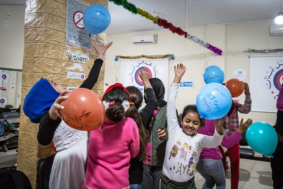 Children in a classroom playing with balloons.