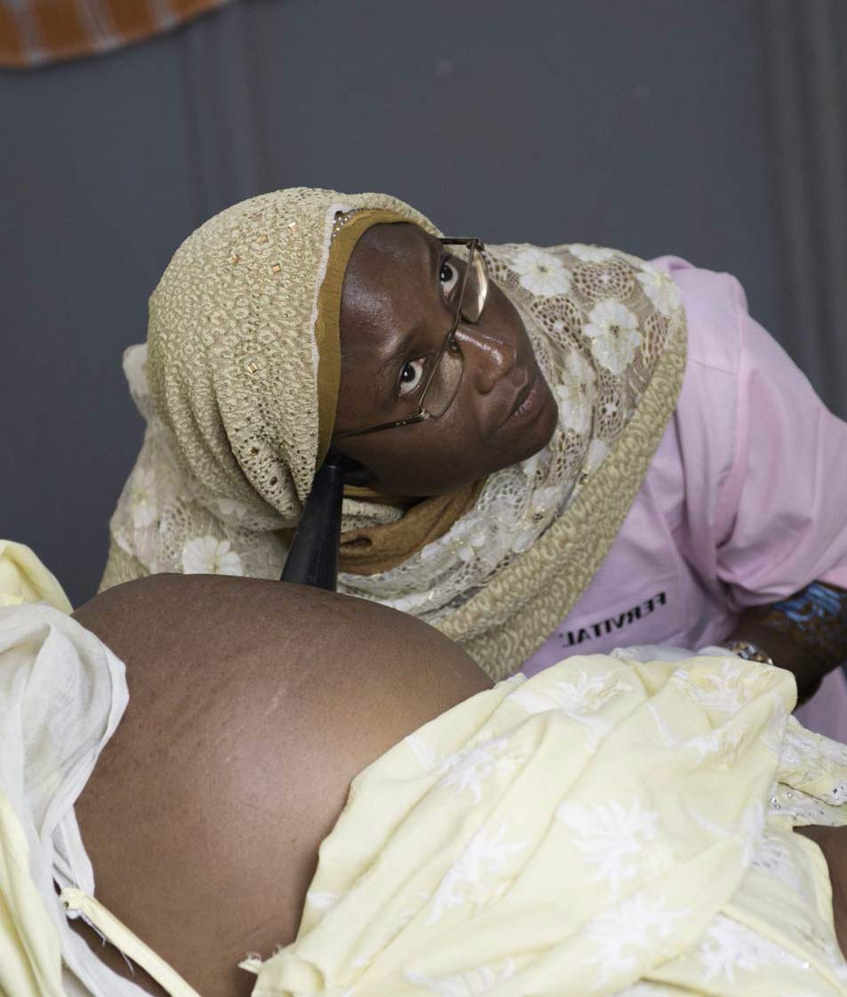 Nurse using stethoscope to listen to pregnant womens baby