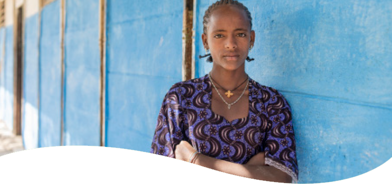 girl standing with arms crossed infront of blue wall