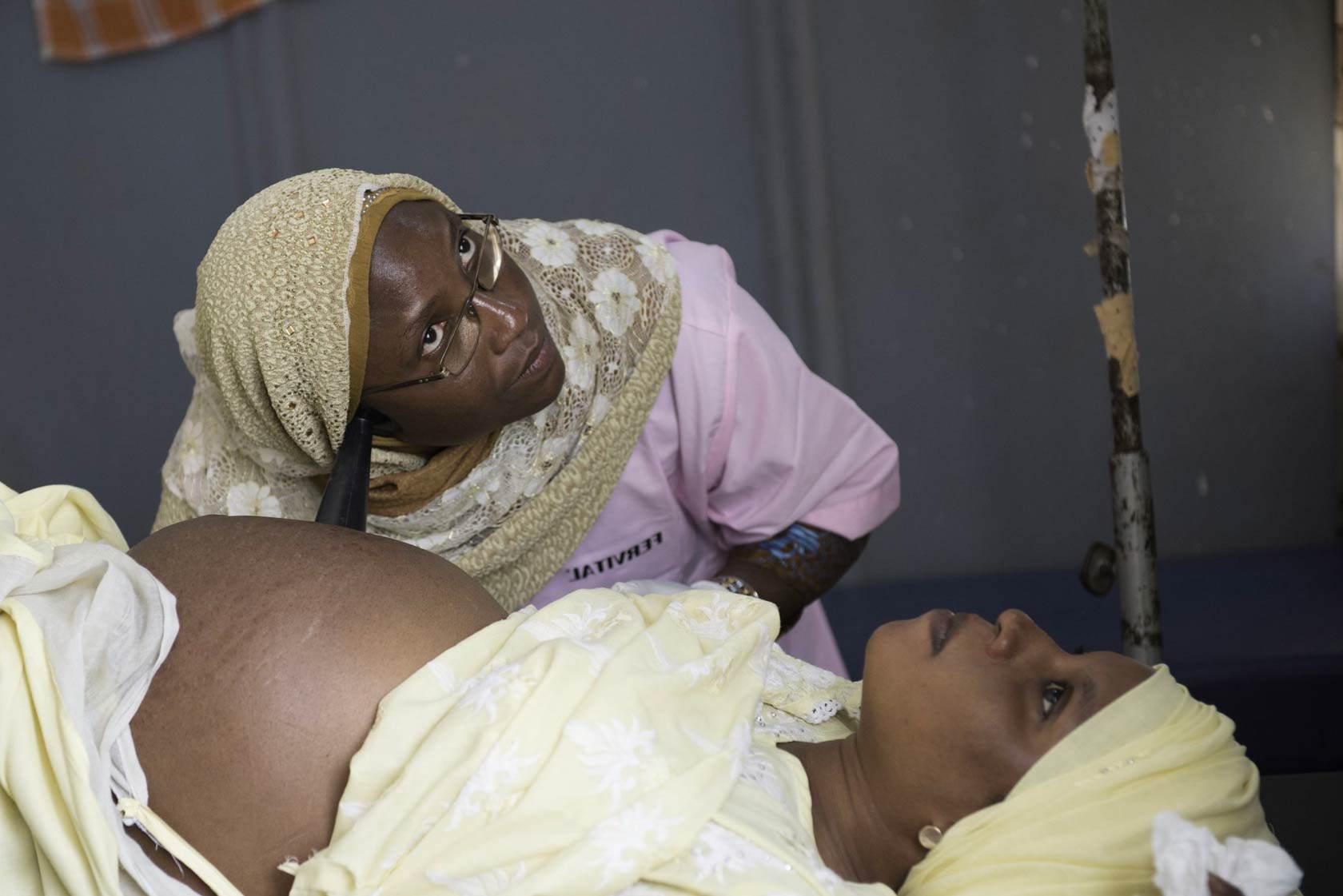 Nurse using stethoscope to listen to pregnant womens baby