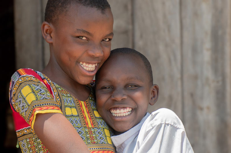Esther, a young girl who participates in Plan’s Adolescent Girls’ Health and Rights project in Tanzania, poses with her younger sister. The project helps fight child marriage, provides care for survivors of violence, and teaches girls about their health.