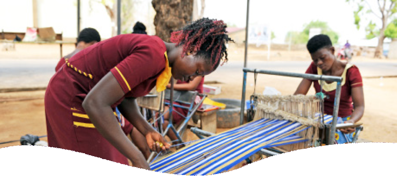 young african students working on a loom making a long fabric