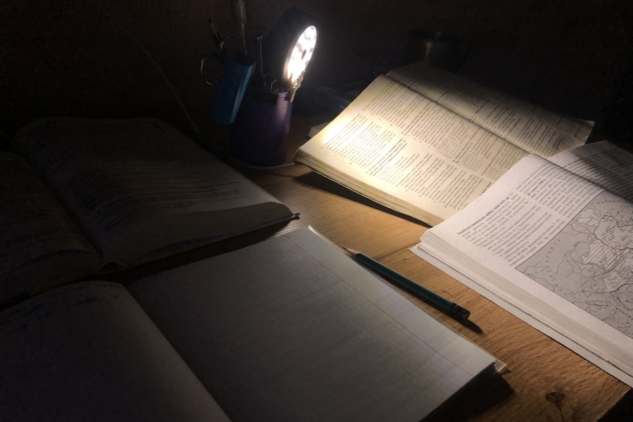 Two books on a desk lit by a table lamp