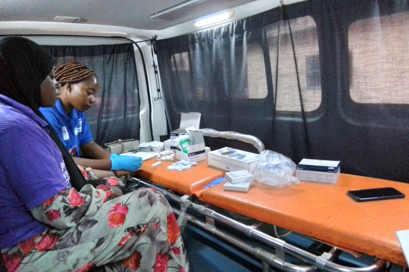 A health worker in a mobile health van tests a woman for HIV