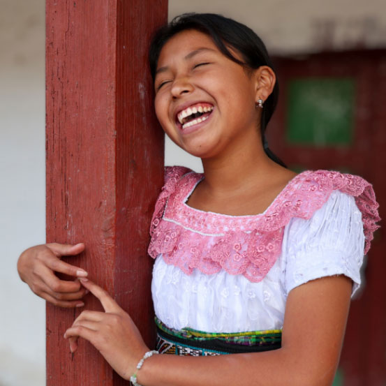 Young woman smiling while leaning against a wooden post
