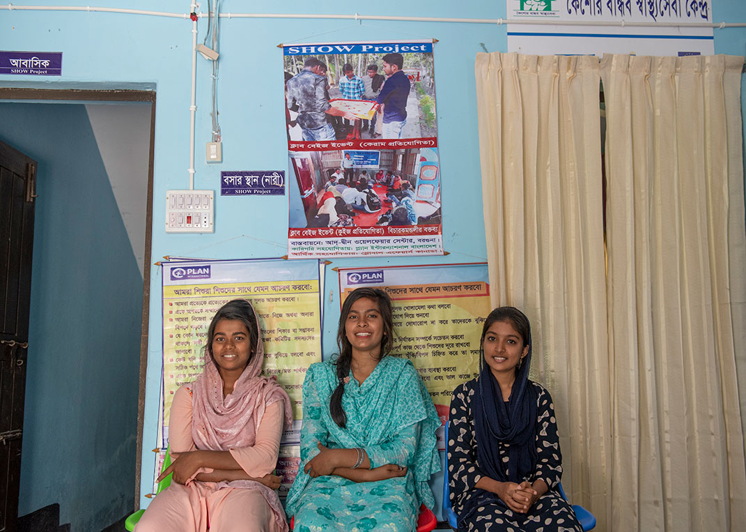 3 girls sit in the waiting room of a Plan International-supported clinic