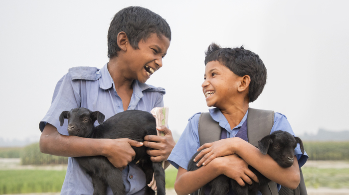 Two boys holding goats