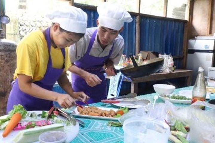 An adolescent girl prepares a dish with a young chef